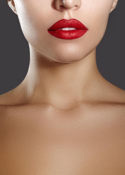 Cosmetics, makeup and trends. Bright lip gloss and lipstick on lips. Closeup of beautiful female mouth with red lip makeup. Beautiful part of female face. Perfect clean skin