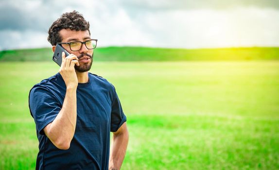 Man calling by cell phone, young man in the field calling by cell phone