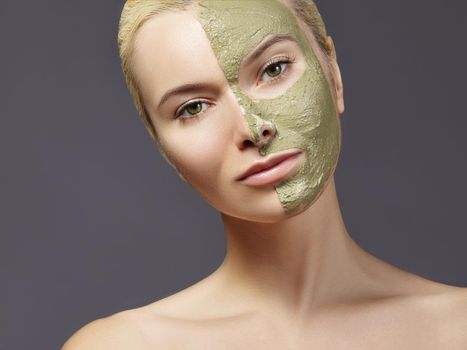 Beautiful Woman Applying Green Facial Mask. Beauty Treatments. Close-up Portrait of Spa Girl Apply Clay Facial mask on grey background