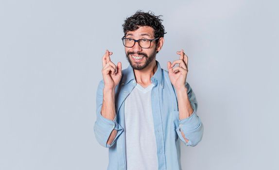 Happy man making a wish, latin guy crossing his fingers making a wish