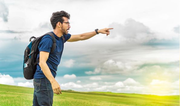 Adventurous man in the field, man with backpack in the field looking