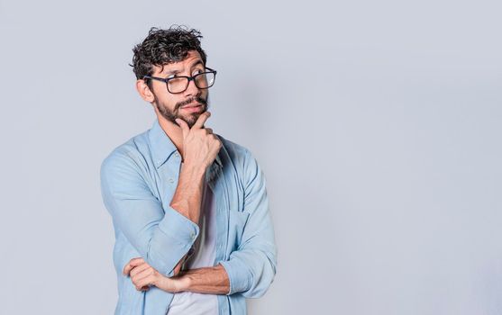 young man wondering with his hand on his chin on an isolated background, a guy thinking with his hand on his chin.