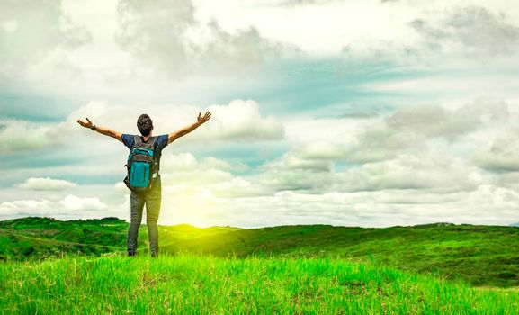 backpacker man in the field spreading his hands, concept of successful man spreading his hands
