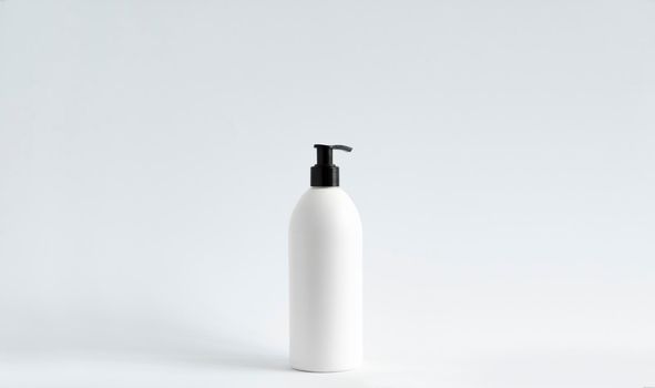White plastic bottle with shampoo, conditioner or shower gel on a white background. Mock up template for design
