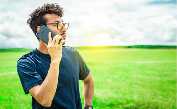 Man calling by cell phone, young man in the field calling by cell phone