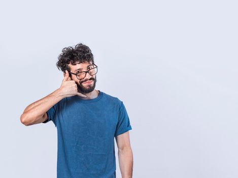 Attractive caucasian young male in casual clothes imitates telephone conversation, keeps hand near ear as if holding mobile phone