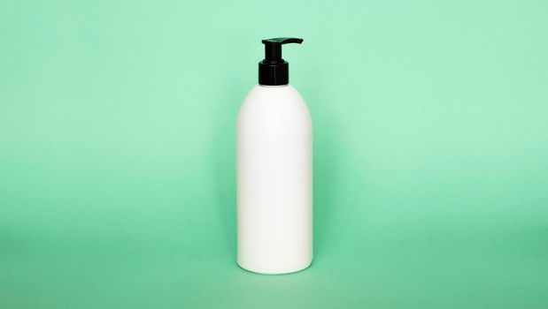 White plastic bottle with shampoo, conditioner or shower gel on a green background. Mock up template for design