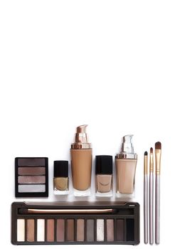 Cosmetics in natural colors and brushes isolated on white background. Makeup tools and accessories. Brow eyeshadows, naturel skin foundation for clean ton on face, nail polish, make-up brushes.