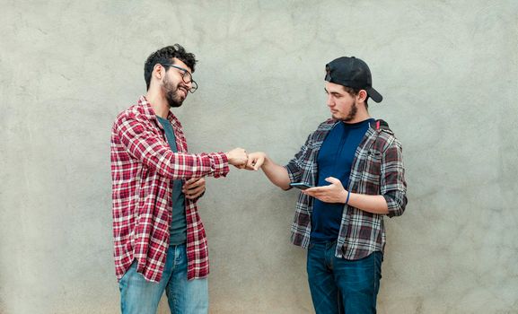 Two young men clashing their fists, image of two young men bumping their fists in a friendly way, close up of two fists bumping in a friendly way