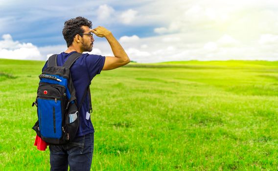 Adventurous man in the field, man with backpack in the field looking