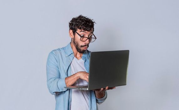 Handsome guy checking his laptop isolated, surprised man checking his laptop, guy with laptop.