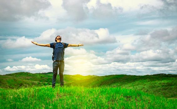 backpacker man in the field spreading his hands, concept of successful man spreading his hands