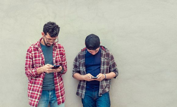 Two guys checking their cell phones, Smiling attractive young people checking their cell phones, Two guys with their cell phones