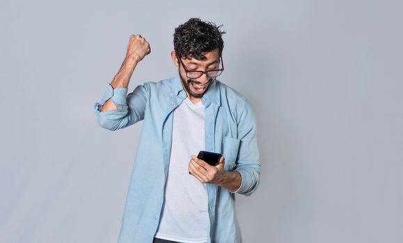 Happy man holding a smartphone and celebrating, Excited guy looking at his smartphone