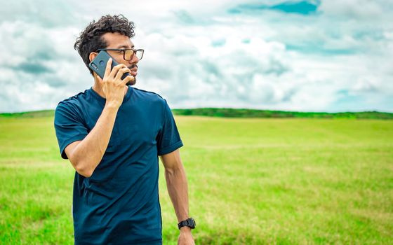 Man calling by cell phone, young man in the field calling by cell phone