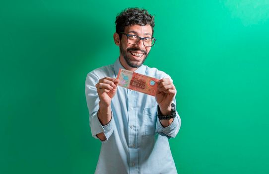 Latin man isolated a money bill, happy guy with a 500 cordobas bill, a 500 cordobas bill.