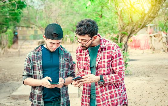 man showing his cell phone to another guy, two guys checking their cell phones, Two young men comparing their cell phones