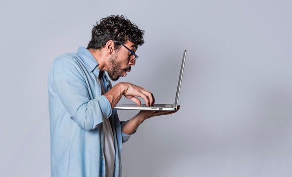 Handsome guy checking his laptop isolated, surprised man checking his laptop, guy with laptop.