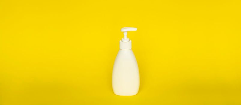 Large white plastic bottle with pump dispenser on yellow background. Mock up template for design