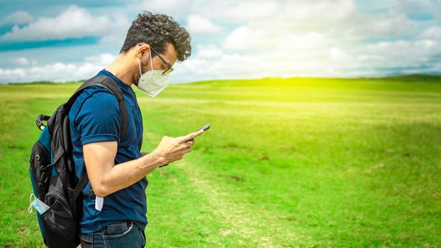Adventurous man in the field with phone, man with backpack in the field chatting
