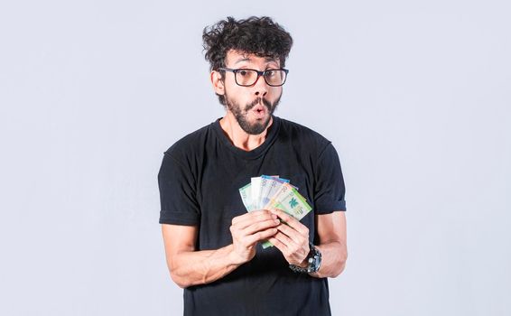 Amazed man with money in hand, man in glasses amazed with banknotes in hand, concept of man earning money