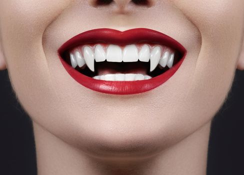 Sexy Female Vampire Lips. Monster Smile. Halloween Style with Red Blood Makeup Lip. Masquerade Look with Terrible Fags on Black Background