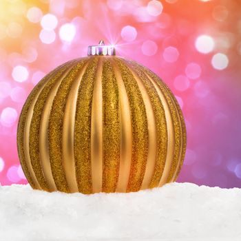 Golden Christmas ball on snow over festive defocused background with copy-space