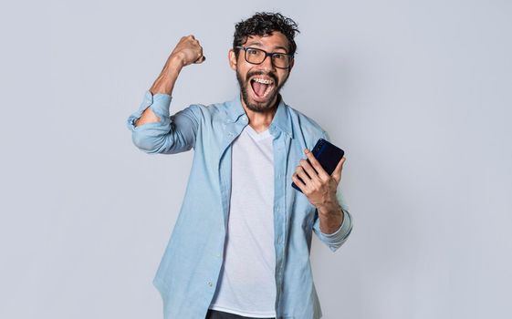 Happy man holding a smartphone and celebrating, Excited guy looking at his smartphone