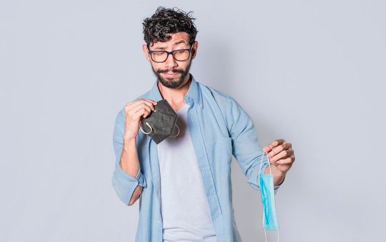 Man deciding to wear surgical mask, Latin man deciding to wear surgical mask on isolated background