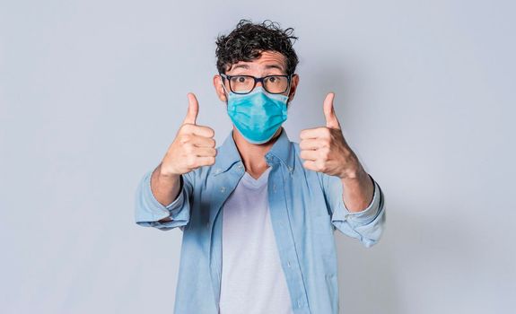 Man with mask on and thumbs up, Latino guy giving thumbs up with mask on.