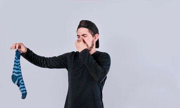 A man with a sock in his hand covering his nose, a guy with a stinky sock in his hand, smelly socks concept