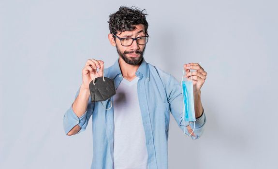 Man deciding to wear surgical mask, Latin man deciding to wear surgical mask on isolated background
