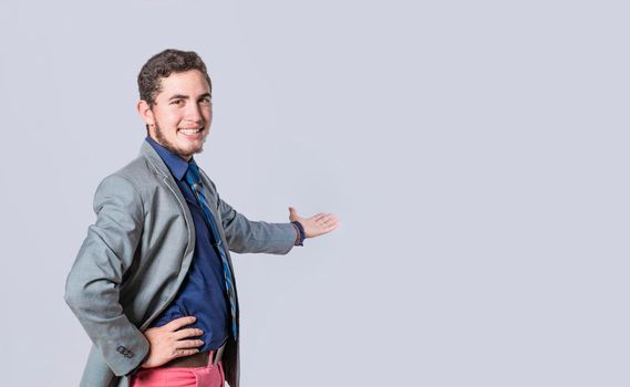 Man pointing back and presenting a product, man in a suit welcoming, man looking at the camera presenting a product, person inviting