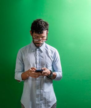 Man checking his cell phone isolated, young man in glasses checking his cell phone isolated