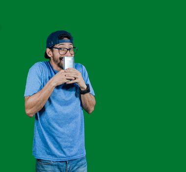 boy in glasses smiling with his cell phone, young man in cap smiling while holding his cell phone on white background, boy smiling covering his mouth with cell phone