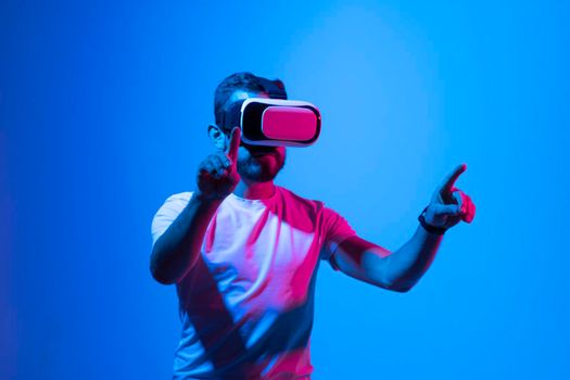 Vitrual reality concept. Man are playing a game in virtual reality. Young man in VR glasses are gaming with realistic holograms in simulator. Entertainment and leisure concept. Modern technologies