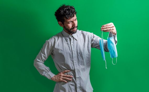 Man deciding to wear surgical mask, Latin man deciding to wear surgical mask on isolated background
