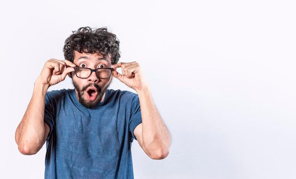 Surprised glasses man holding his glasses, Emotive young caucasian man staring through big glasses,