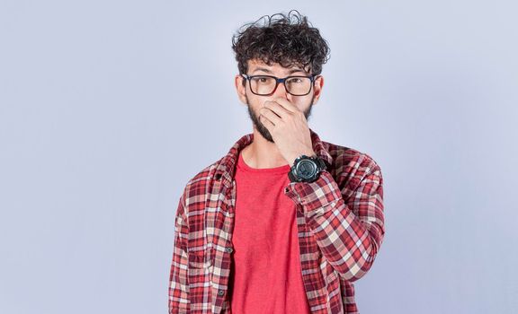 Close up of a man covering his nose, a guy with a face of unpleasant odors, Latino man covering his nose