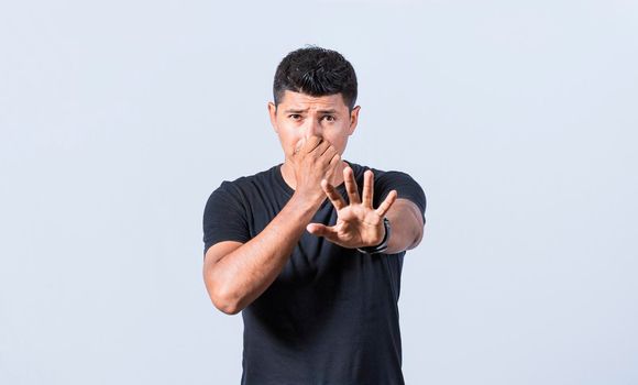 Annoyed man covering his nose, Confused unhappy man grabbing nose with fingers and stretching hand out feeling disgusted