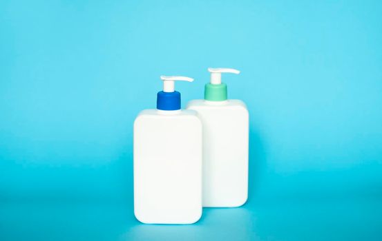 Shampoo or hair conditioner bottles with dispenser pump on blue background