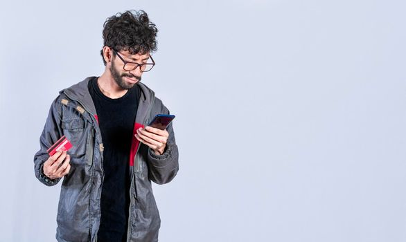 Man holding credit card and cell phone, guy paying from his phone with credit card, electronic payment concept