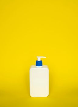 Liquid container for gel, lotion, cream, shampoo, bath foam. Cosmetic plastic bottle with blue dispenser pump on yellow background. Cosmetic packaging mockup with copy space