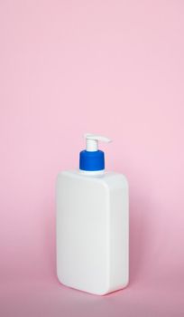 White unbranded dispenser bottle on pink background. Cosmetic packaging mockup with copy space