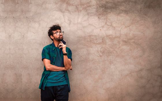 Pensive young latin man with hands in his pocket, pensive young man looking up