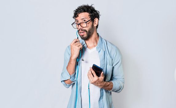 handsome man talking with headset holding cellphone , young man in glasses with earphones isolated