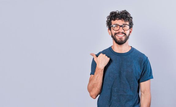 Cheerful bearded man with a friendly smile shows you the direction to a nice place, a friendly guy pointing his thumb to his right