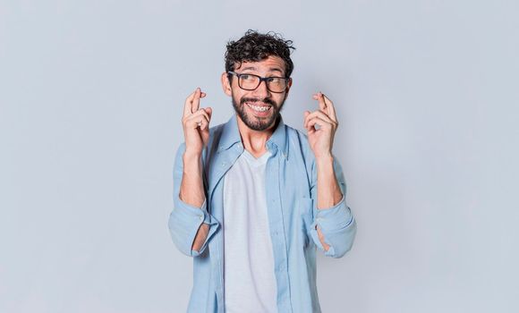 Happy man making a wish, latin guy crossing his fingers making a wish