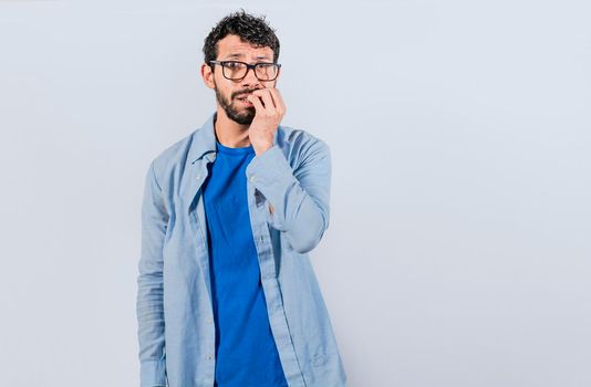 Guy with worried expression on isolated background, Nervous young male with worried expression, bites nails and looks anxiously. Nervous man concept