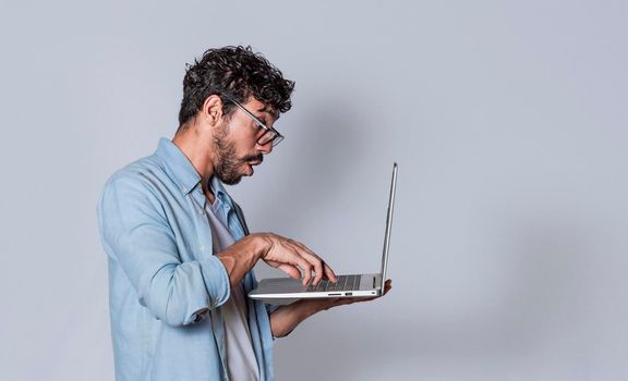 Handsome guy checking his laptop isolated, surprised man checking his laptop, guy with laptop.